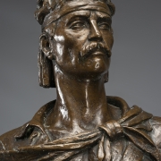 Escultura em bronze representando o "gaúcho laçador".  Figura masculina, em pé, apoiada sobre a perna esquerda, corpo e cabeça virada para frente. A cabeça, com cabelos na altura do pescoço, possui uma faixa amarrada na testa, barba e bigode. 